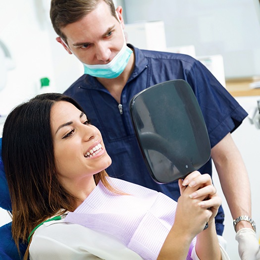 Patient holding hand mirror, admiring her smile