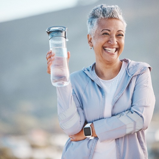 Mature woman standing outside, holding a water bottle