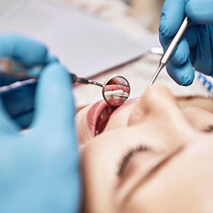 Gloved hands holding dental instruments during patient exam