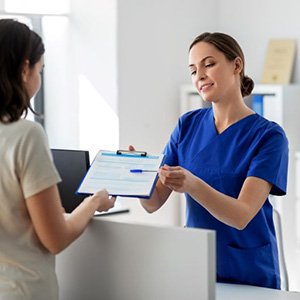 Dental team member helping patient fill out paperwork